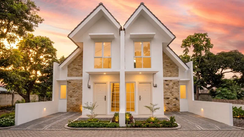 Rumah dua lantai dengan taman depan saat senja